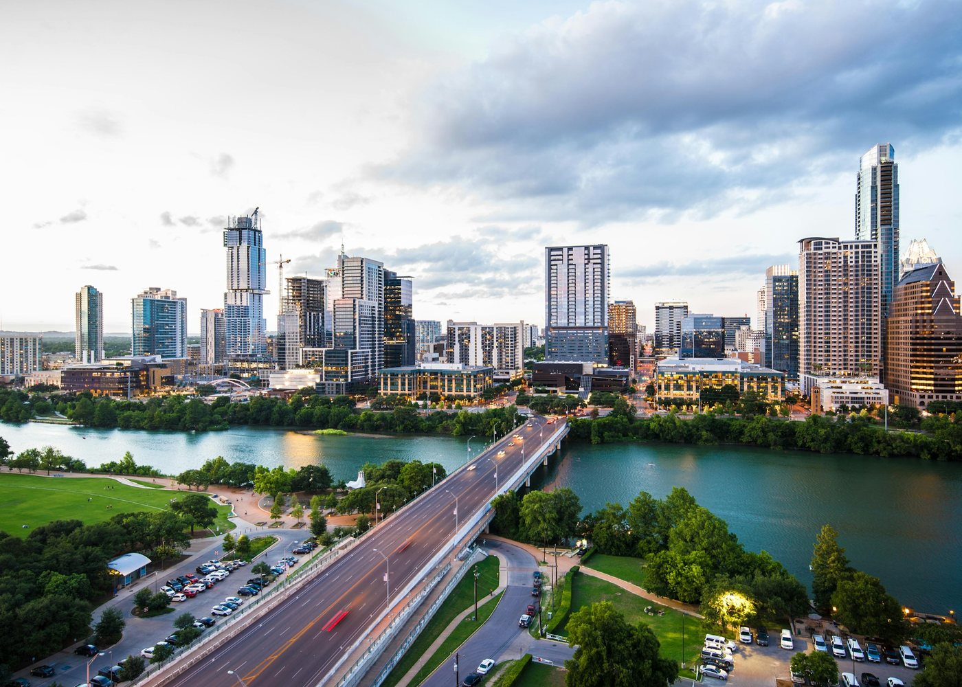 The Austin skyline over Lady Bird Lake on a bright afternoon, with bridges and riverside parks in the foreground.
